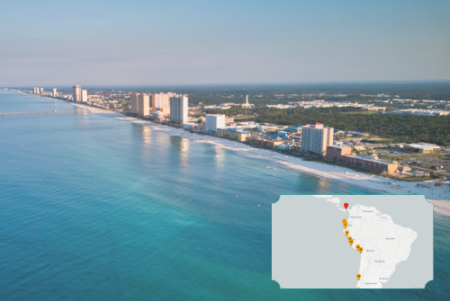 Luftaufnahme einer langen Küstenlinie mit türkisblauem Meer und weißem Sandstrand vor einer Reihe moderner Hochhäuser und Hotels in Panama City Beach. Unten rechts ist eine kleine Karten-Grafik von Südamerika eingeblendet, die mit Markierungen die Reiseroute entlang der Pazifikküste zeigt.